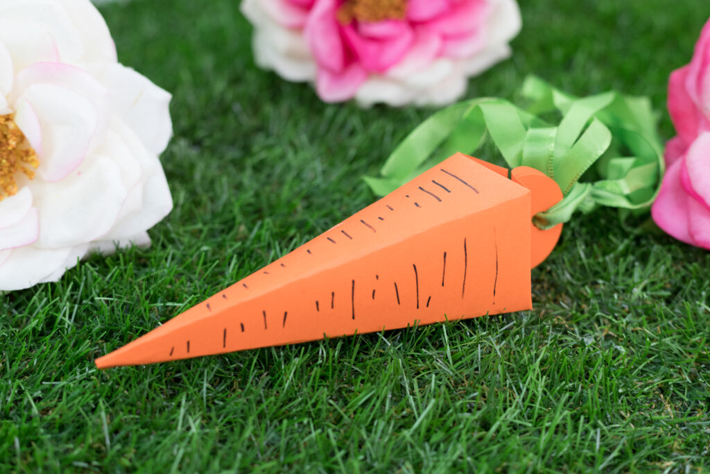 A 3D carrot made with orange paper. The stem is mad with green ribbon.